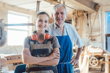 Senior master carpenter with his granddaughter in the wood workshop