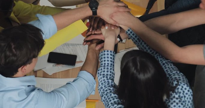 Multi-ethnic business people sticking their hands together in office. Success business , start-up, teamwork concept.