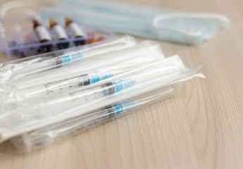 Syringes in the package, ampoules with medication and a mask on a light background.The concept of prevention of viral diseases.