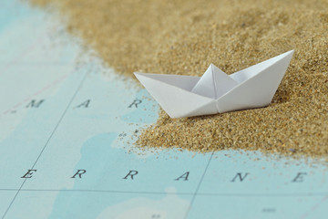 Paper boat on a map with sand - Immigration concept
