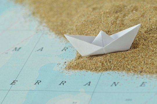 Paper boat on a map with sand - Immigration concept