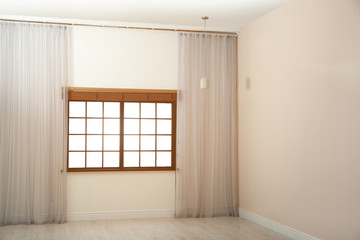 Window with beautiful curtains and open blinds in empty room