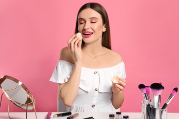 Beauty blogger applying lip balm on pink background
