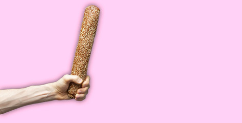isolated hand holding a fresh bread loaf baguette against color background