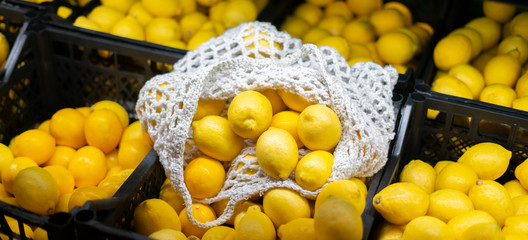 a mesh eco bag with fresh fruits lay on top of crate with food in local farmer grocery store