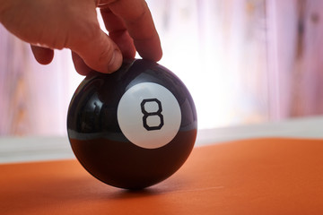 The ball of predictions figure eight on an orange background holds a hand.