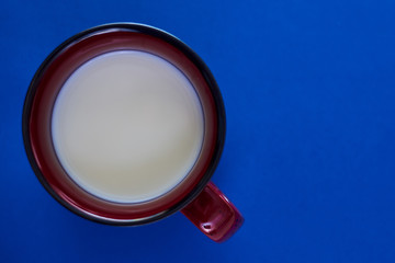Cup with milk on a blue background.