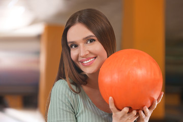 Young woman with ball in bowling club