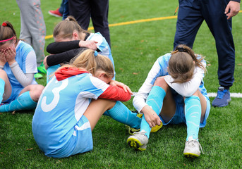 Girl football team players crying, feeling bitterness of defeat
