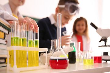Smart pupils making experiment in chemistry class, focus on flask with reagent