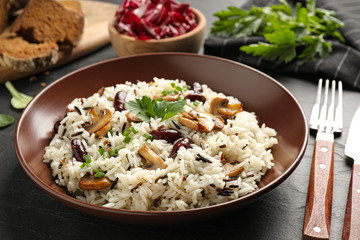 Delicious rice pilaf with mushrooms on black table