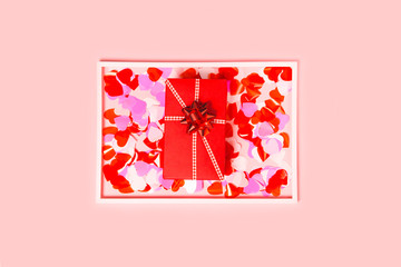 Present box with decorative hearts confetti in white frame on white background. Abstract backdrop. Love and romance concept.