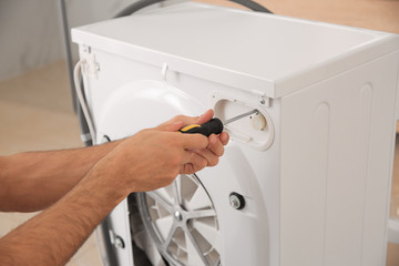 Professional plumber repairing broken washing machine, closeup