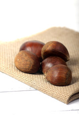 pile of raw sweet chestnuts on canvas napkin isolated on white background