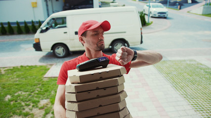 Portrait of upset delivery man in red uniform standing by the house near door. Close-up handsome...