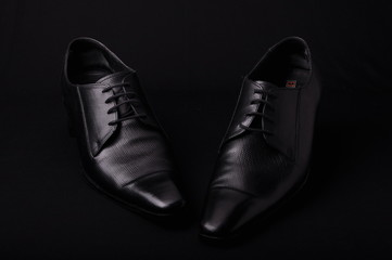 Pair of black shoes on dramatic light black background