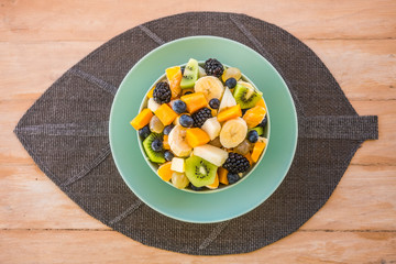 Top view of an inviting fresh fruit salad. Wooden table