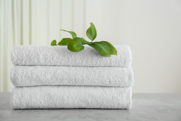 Fresh towels and green branches on light grey stone table in bathroom