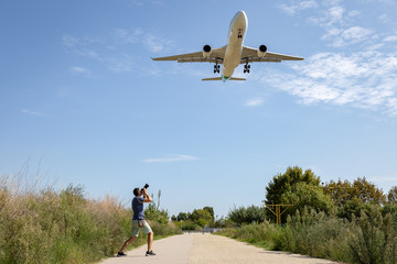 Fototapeta na wymiar Photographer taking photo of an airplane landing