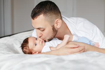 Happy Caucasian father holding newborn baby. Male bearded man parent hugging kissing child daughter son. Authentic lifestyle candid moment. Proud young dad. Family fathers day holiday.