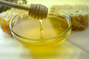 wooden spoon stirs honey in a glass bowl