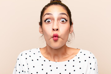 young latin woman with cheerful, carefree, rebellious attitude, joking and sticking tongue out,...
