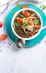 Cooked green lentils with tomatoes, onions and mint in a white bowl 