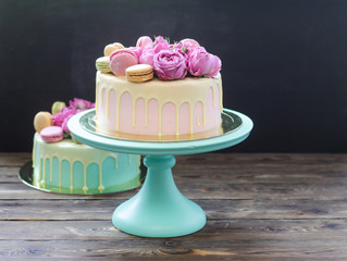 Pink, ivory and turquoise cake with melted white chocolate, fresh roses and french macaroons  