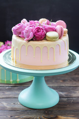Pink, ivory and turquoise cake with melted white chocolate, fresh roses and french macaroons  