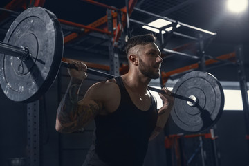 Fototapeta na wymiar Stronger, Young muscular caucasian athlete practicing lunges in gym with barbell. Male model doing strength exercises, training his lower body. Wellness, healthy lifestyle, bodybuilding concept.