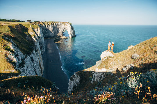 Couple looking at Etretat cliffs along the ocean shore in France