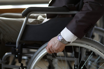 Disability businessman with wheelchair against business office background. Adaptation of people...