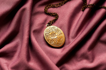 vintage grandma's bronze locket on a purple fabric background - 320834473