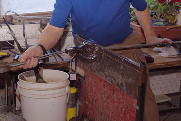 Glass blowing: Using tongs, the glass blower turns the bulb to give it shape.