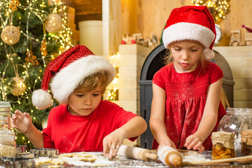 Cookies for Santa Claus. Cute little boy and girl twins preparing Christmas cookies in the kitchen. Funny children making cookies for Santa.