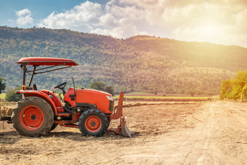 tractor in agriculture field with mountain and blue sky