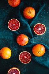 Flat lay food composition with blood oranges on a dark blue background.