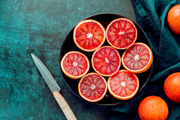 Cutted blood oranges in a plate on a dark blue background. Top view, copy space.