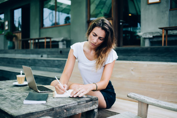 Focused woman writing notes in cafe