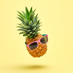 Flying in air pineapple tropical fruit on yellow. Healthy vitamin pineapple in sunglasses, dieting food. Whole sweet fresh fruits. Levitation, falling fly pineapple creative fun concept