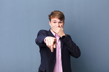 young blonde man laughing at you, pointing to camera and making fun of or mocking you isolated...