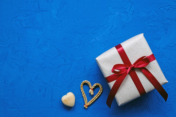 zero waste concept. environmentally friendly wooden, wicker hearts and gift with ribbon on a blue...