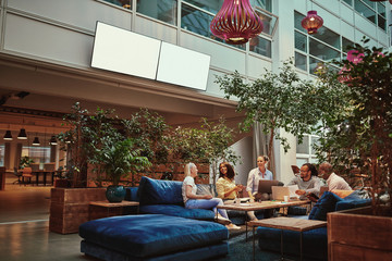 Smiling businesspeople relaxing in the lounge area of an office - obrazy, fototapety, plakaty