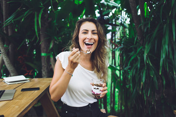 Smiling woman eating dessert in cafe