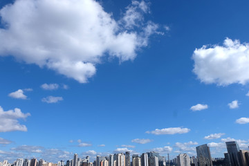 Flat cityscape with blue sky, white clouds and sun. Modern city skyline flat panoramic background....