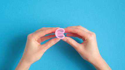 Menstrual cup in female hands top view. Alternative feminine hygiene product. Women health care concept.