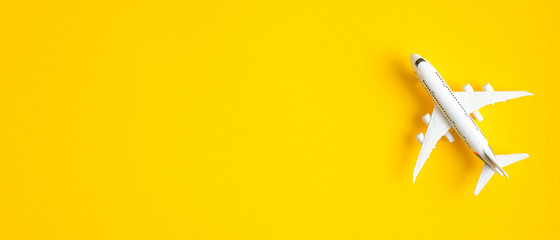 Miniatuur speelgoed vliegtuig op gele achtergrond met kopie ruimte. Zomervakantie vliegreizen per vliegtuig concept. Reisbureau banner ontwerpsjabloon, banner of header mockup