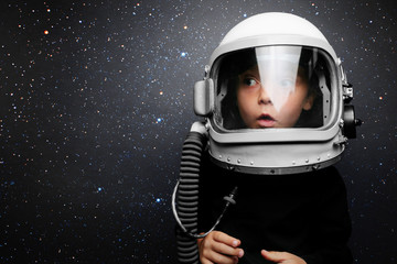 A small child imagines himself to be an astronaut in an astronaut's helmet. Elements of this image furnished by NASA - obrazy, fototapety, plakaty