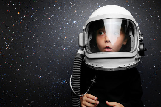 A small child imagines himself to be an astronaut in an astronaut's helmet. Elements of this image furnished by NASA