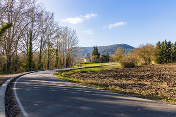 View of the road that borders Lake Banyoles with the church of Sta Maria of Porqueras in the background, Catalonia, Spain